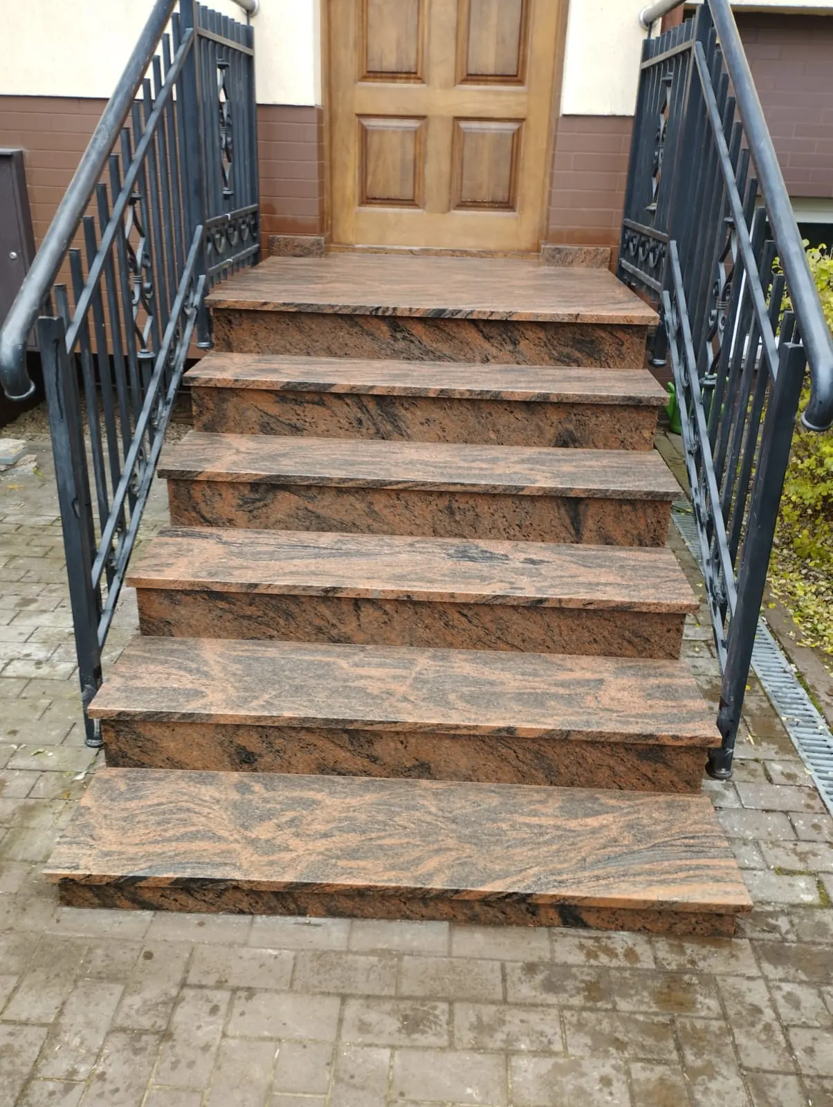 Brązowe schody granitowe przy wejściu z metalową balustradą