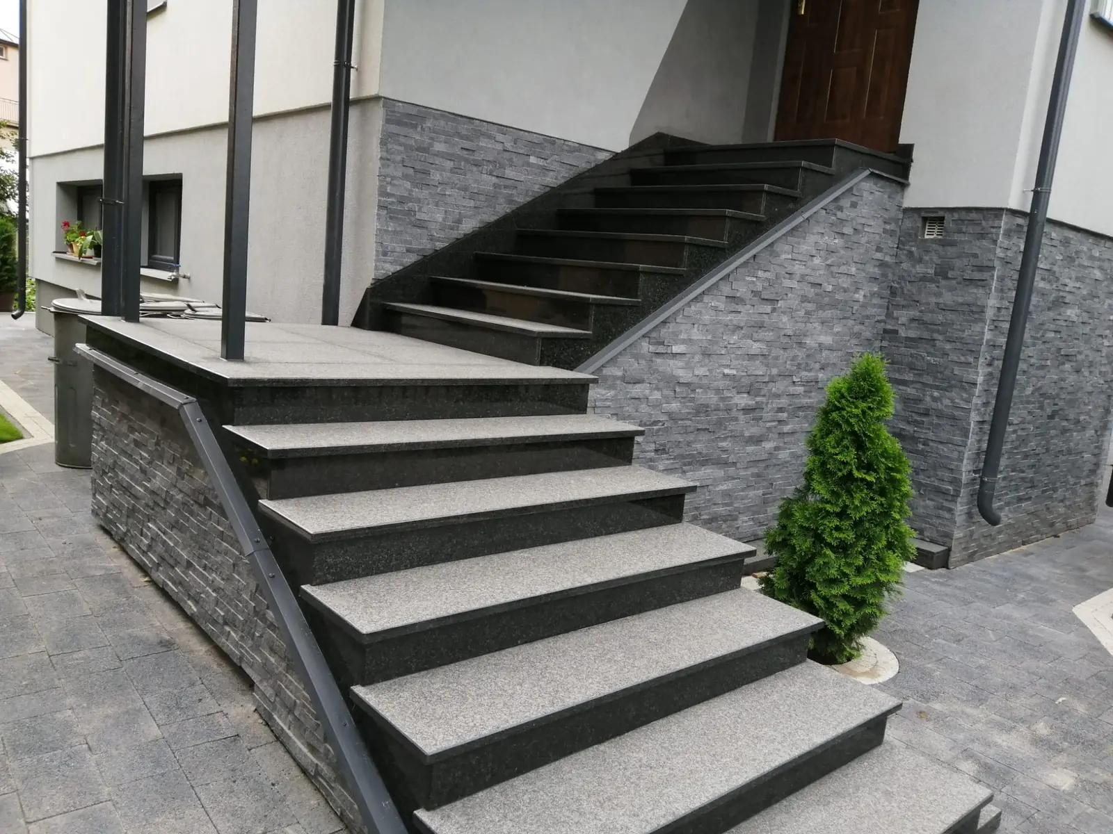 Dwubiegowe zewnętrzne schody granitowe przy nowoczesnej elewacji