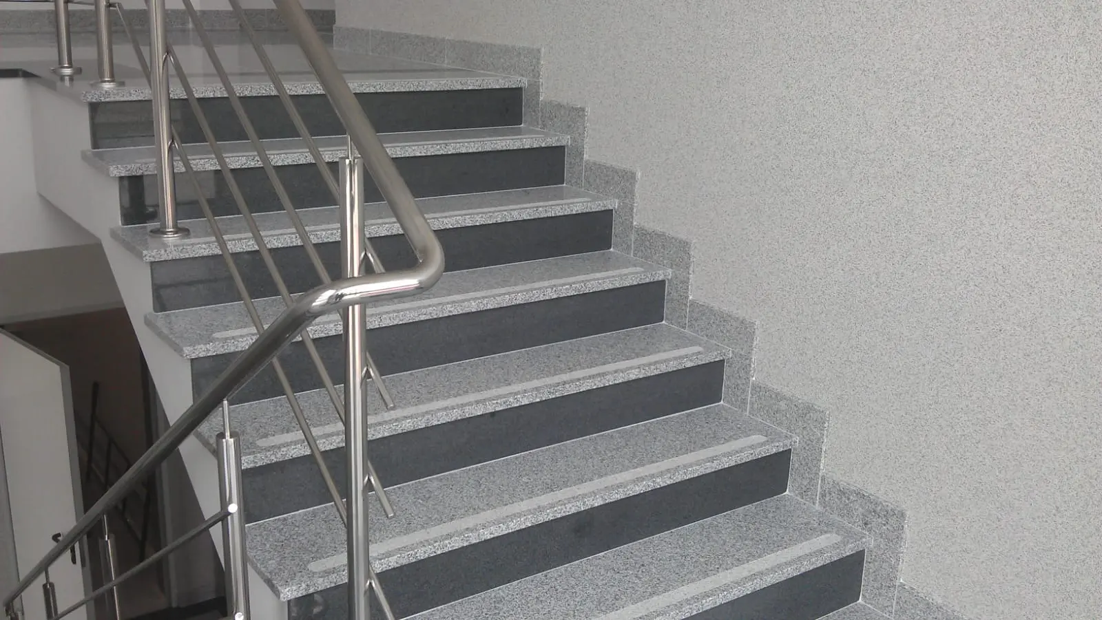 Ciemne kamienne schody wewnętrzne z metalową balustradą