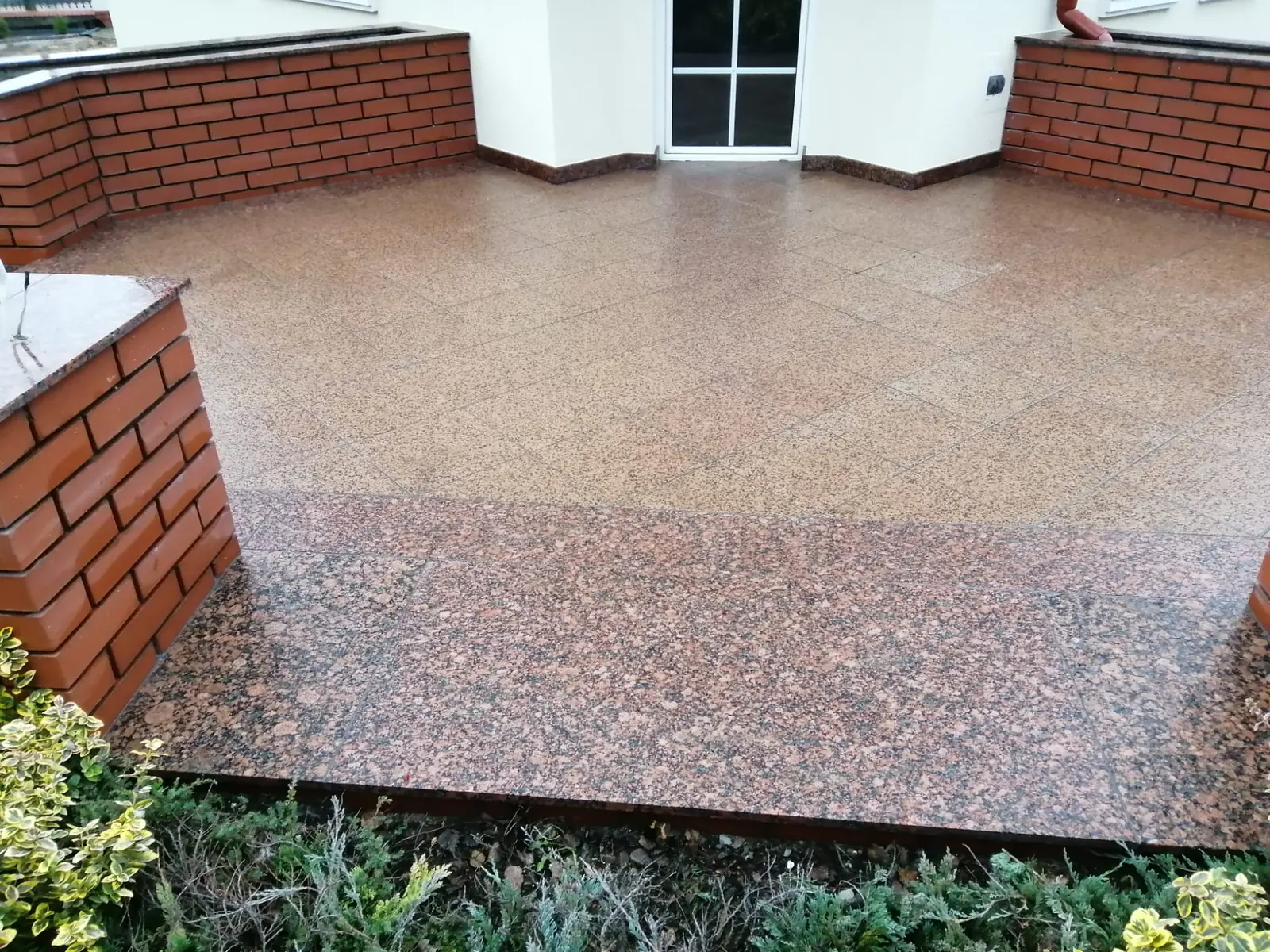 Granitowy taras i schody przy elewacji wykończonej czerwoną cegłą