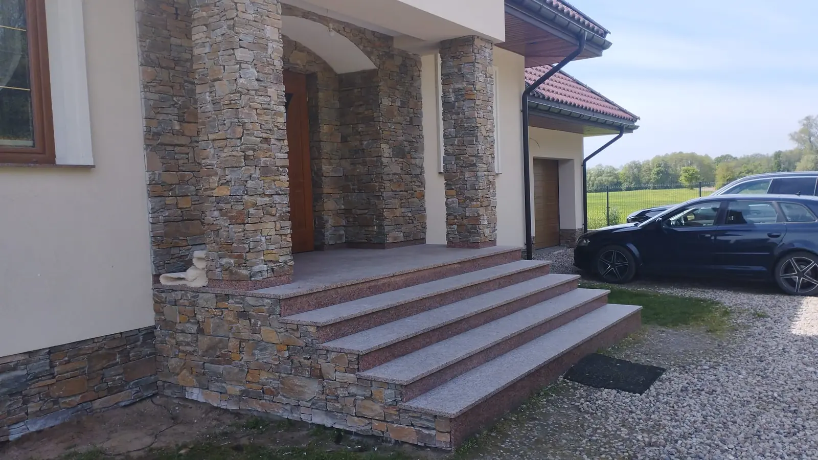 Szerokie schody granitowe przy wejściu wykończonym kamieniem naturalnym